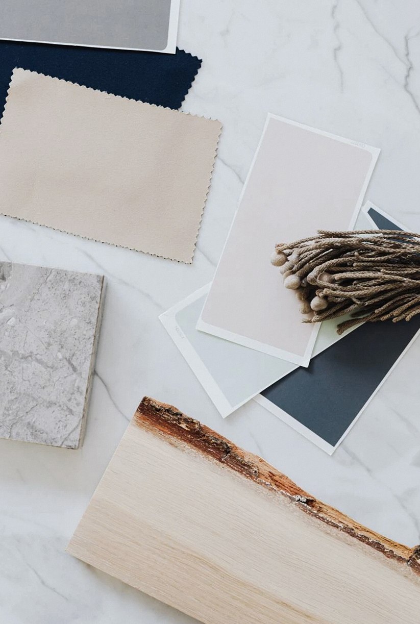 Flat lay of material samples for interior design including wood, marble, and textiles.